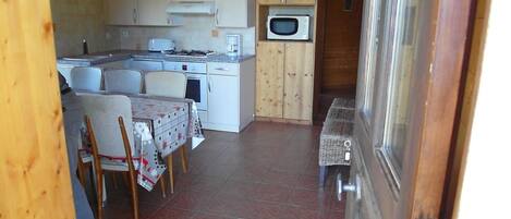 A compact kitchen with white cabinets, a microwave, and a dining area with a table and chairs.