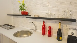 Eine Küche mit einem Spülbecken, einer roten Pflanze, einer roten Vase, einer Champagnerflasche und einer Kaffeemaschine.
