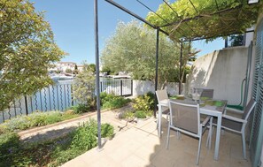 A balcony with a table and chairs, overlooking a body of water with boats and buildings in the background.