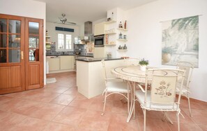 A kitchen with a central island, white chairs, and a dining table.