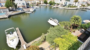 Un port de plaisance où sont amarrés des bateaux, entouré d’immeubles résidentiels aux toits couverts de tuiles.