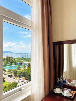 Ein Hotelzimmer mit großem Fenster mit Blick auf einen Pool und eine Stadtlandschaft.