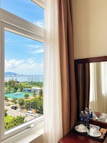 Quarto de hotel com uma janela grande que dá para uma piscina e uma vista da cidade.