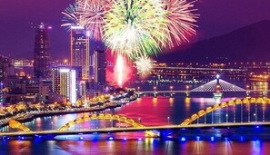 Un paisaje urbano con un río, un puente y fuegos artificiales en el cielo.