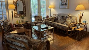 En stue med sofa, stole, sofabord og lampe. Der er et spejl, et vindue og et billede på væggen.