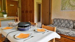 A dining area with a table set for four, a grill, and a sofa in the background. - GRAND CAP 1 - APPT 4 PERS TIGNES - PEACE AND NATURE (Tignes)