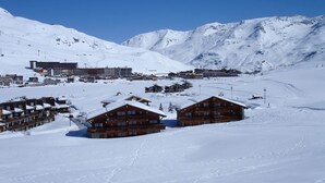 A snow-covered mountain area with wooden cabins and a ski resort in the background. - GRAND CAP 1 - APPT 4 PERS TIGNES - PEACE AND NATURE (Tignes)