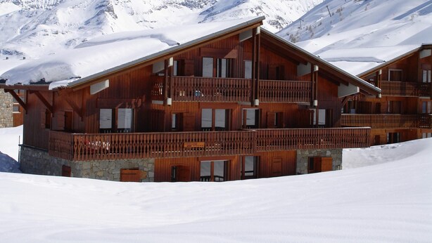 A wooden chalet with multiple balconies, set against a snowy mountain backdrop. - GRAND CAP 1 - APPT 4 PERS TIGNES - PEACE AND NATURE (Tignes)