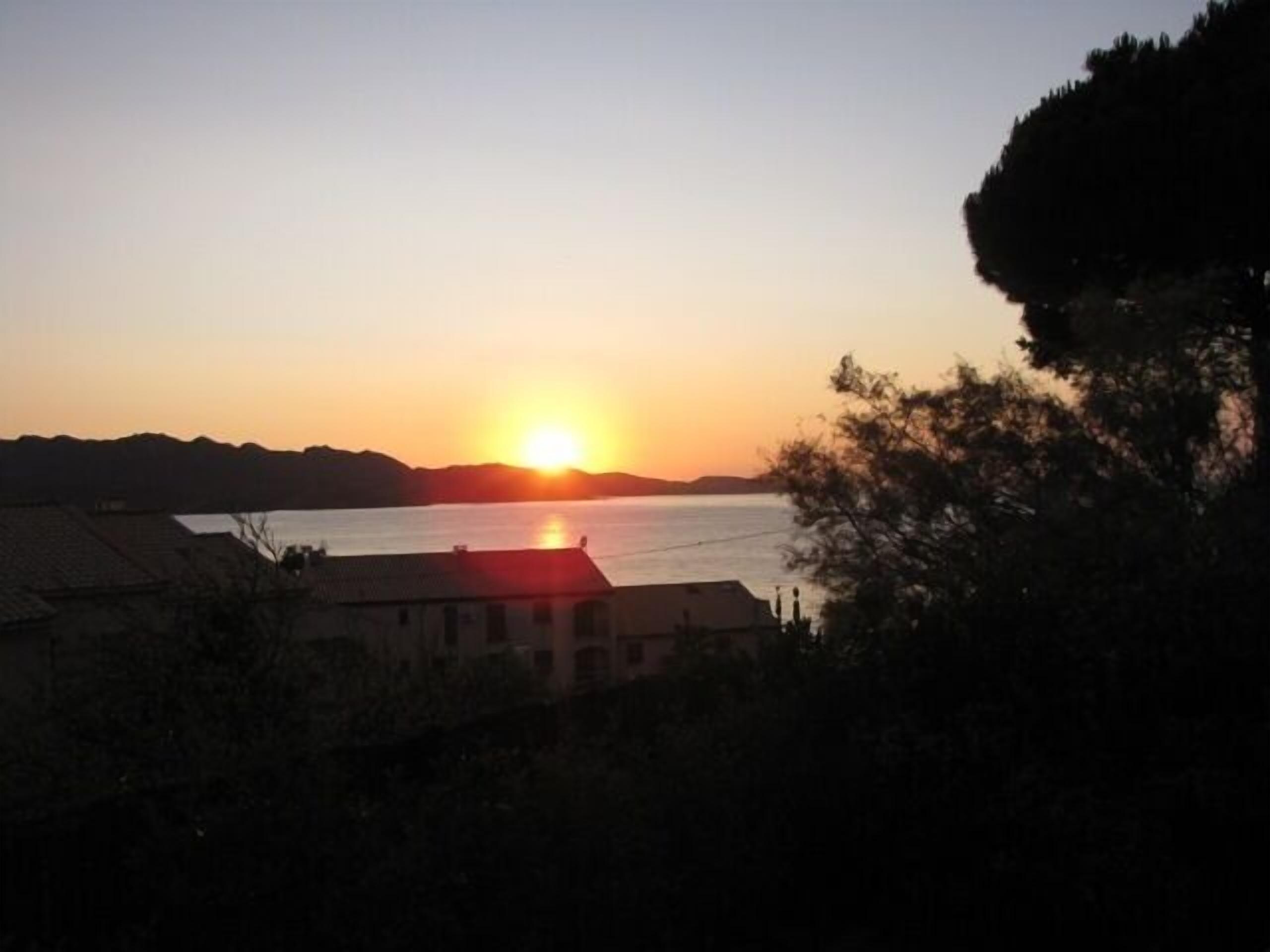 A sunset over a body of water with a building in the foreground.