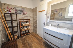 A bathroom with a wooden shelf unit, a large mirror, and a white sink.