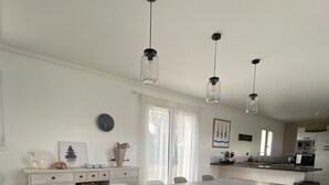Una cocina moderna con comedor, que incluye una mesa grande, sillas e iluminación colgante.