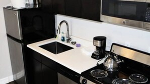 A compact kitchen with a stainless steel refrigerator, a double sink, a coffee maker, and a microwave. - 2-Bedroom Luxury Suite with Kitchen in Minneapolis Boutique Hotel (Minneapolis)