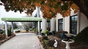 A building with a sign reading "erik's retreat" at the entrance, surrounded by a landscaped garden with statues and a fountain. - 2-Bedroom Luxury Suite with Kitchen in Minneapolis Boutique Hotel (Minneapolis)