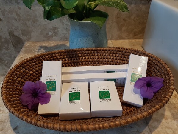 A wicker basket containing several white boxes with green logos, a purple flower, and a potted plant.