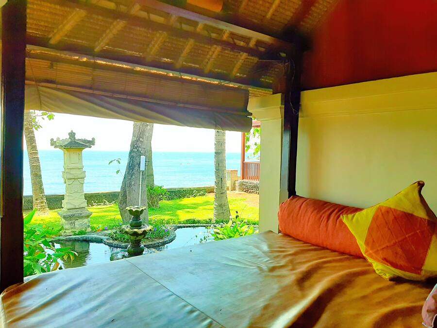 Uma cama com vista para um jardim e o mar.
