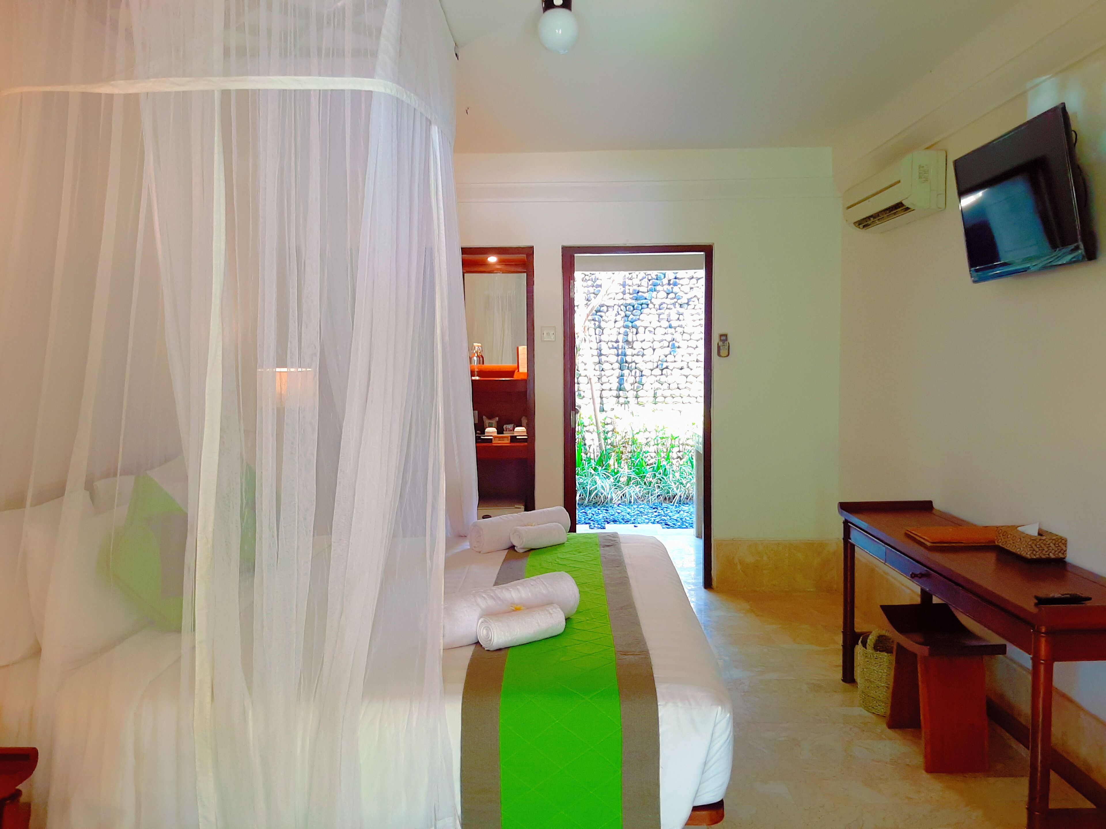 A bedroom with a bed, a TV, and a view of the outside.