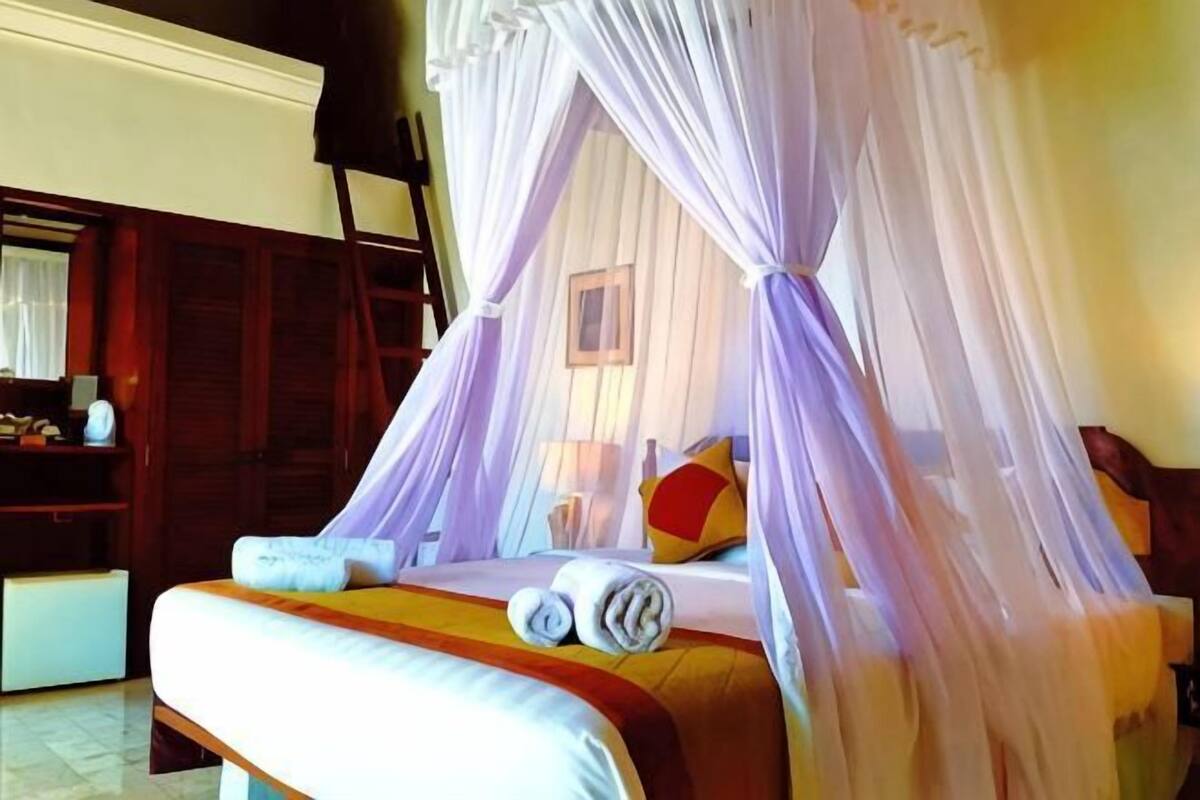 A bed with a canopy, a bedside table, and a chair.