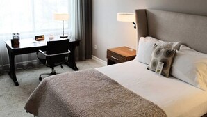 A hotel room with a large bed, a desk with a chair, a nightstand, and a window with curtains. - Executive Queen Room in Minneapolis Boutique Hotel (Minneapolis)