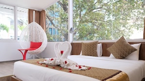 A hotel room with a large bed, a white chair, and a view of trees through the window. - The Umi Hotel (Ho Chi Minh City)