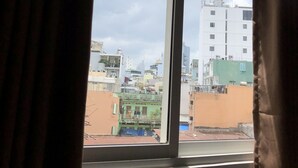 A window with a view of a cityscape, including buildings and a clear sky. - The Umi Hotel (Ho Chi Minh City)