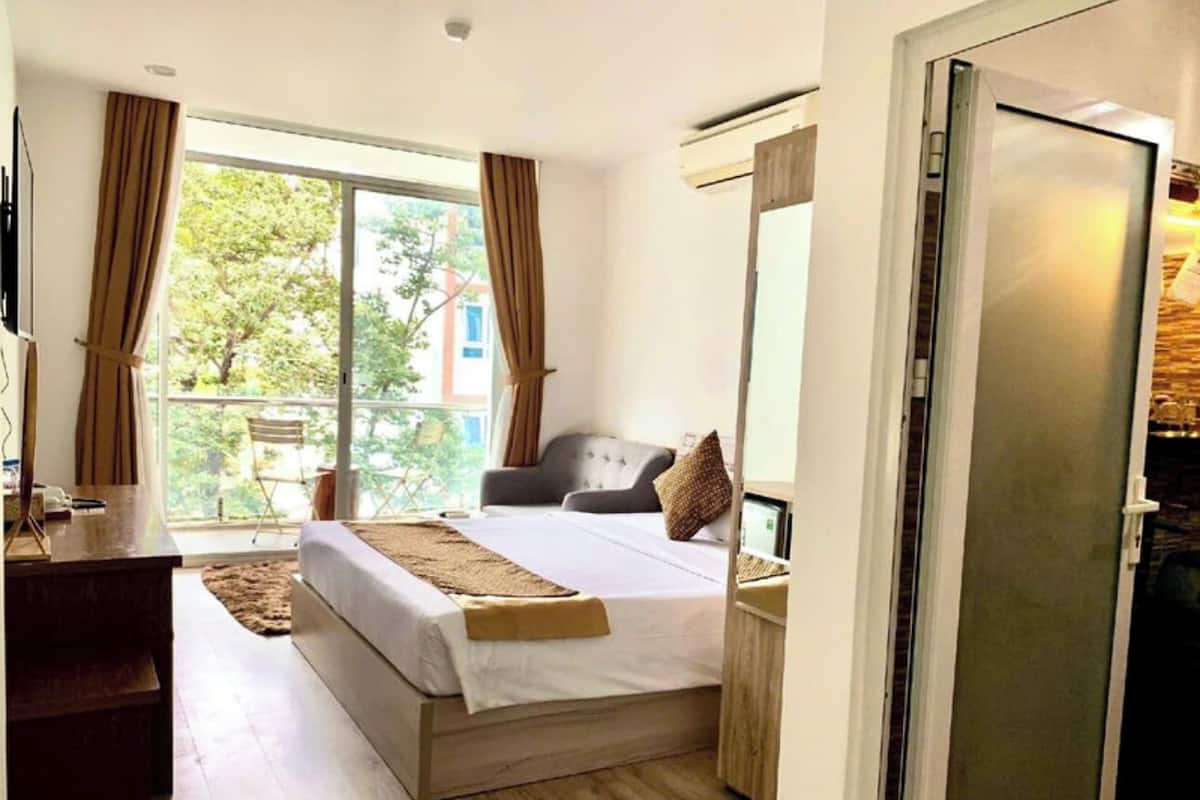 Et soveværelse med seng, skrivebord og skydedør til en balkon.