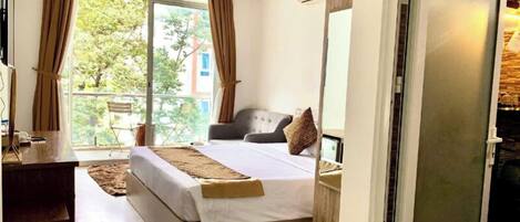 Ein Schlafzimmer mit Bett, Schreibtisch und einer Schiebetür zum Balkon.