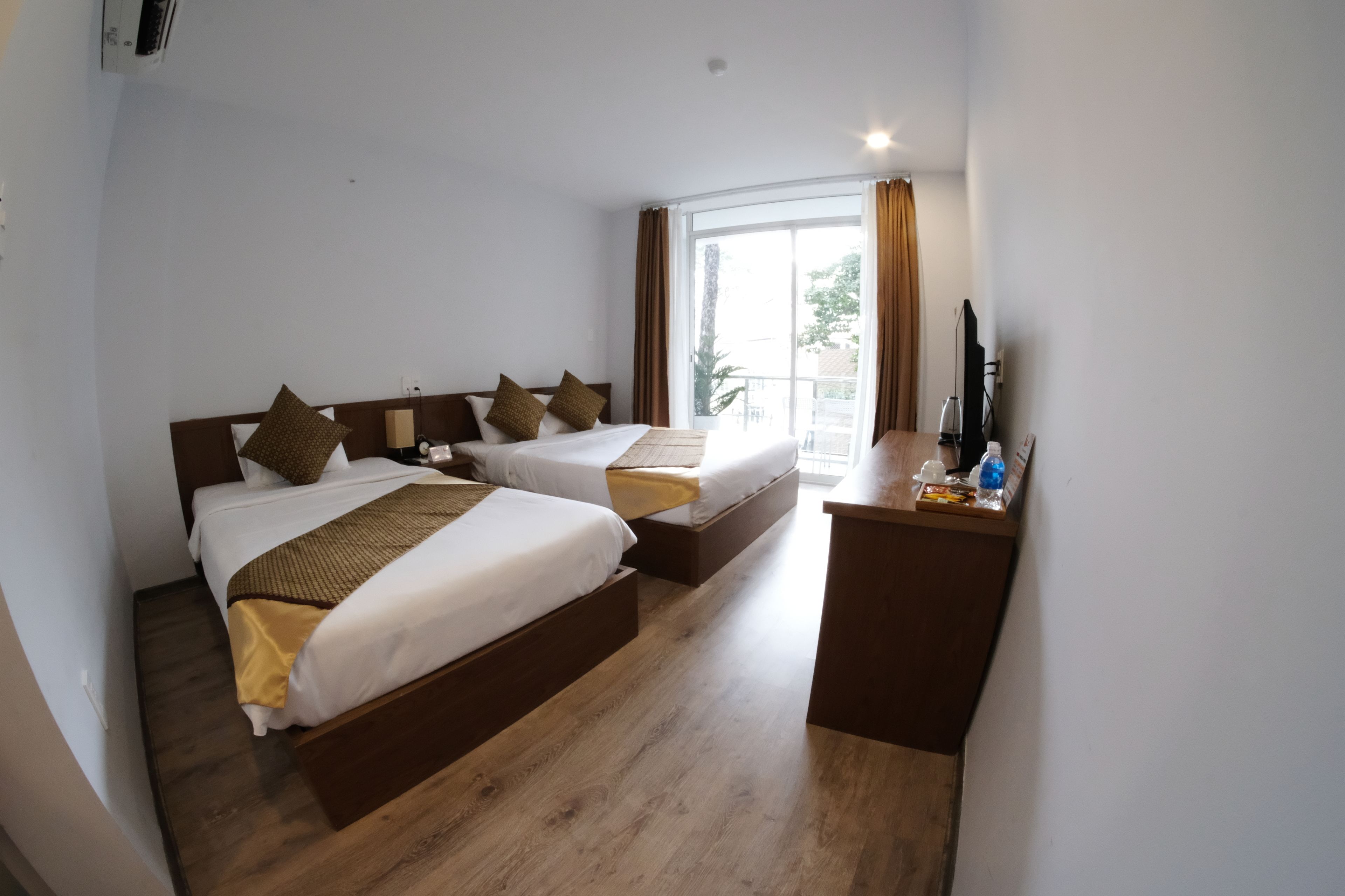 A hotel room with two beds, a desk, and a large window.
