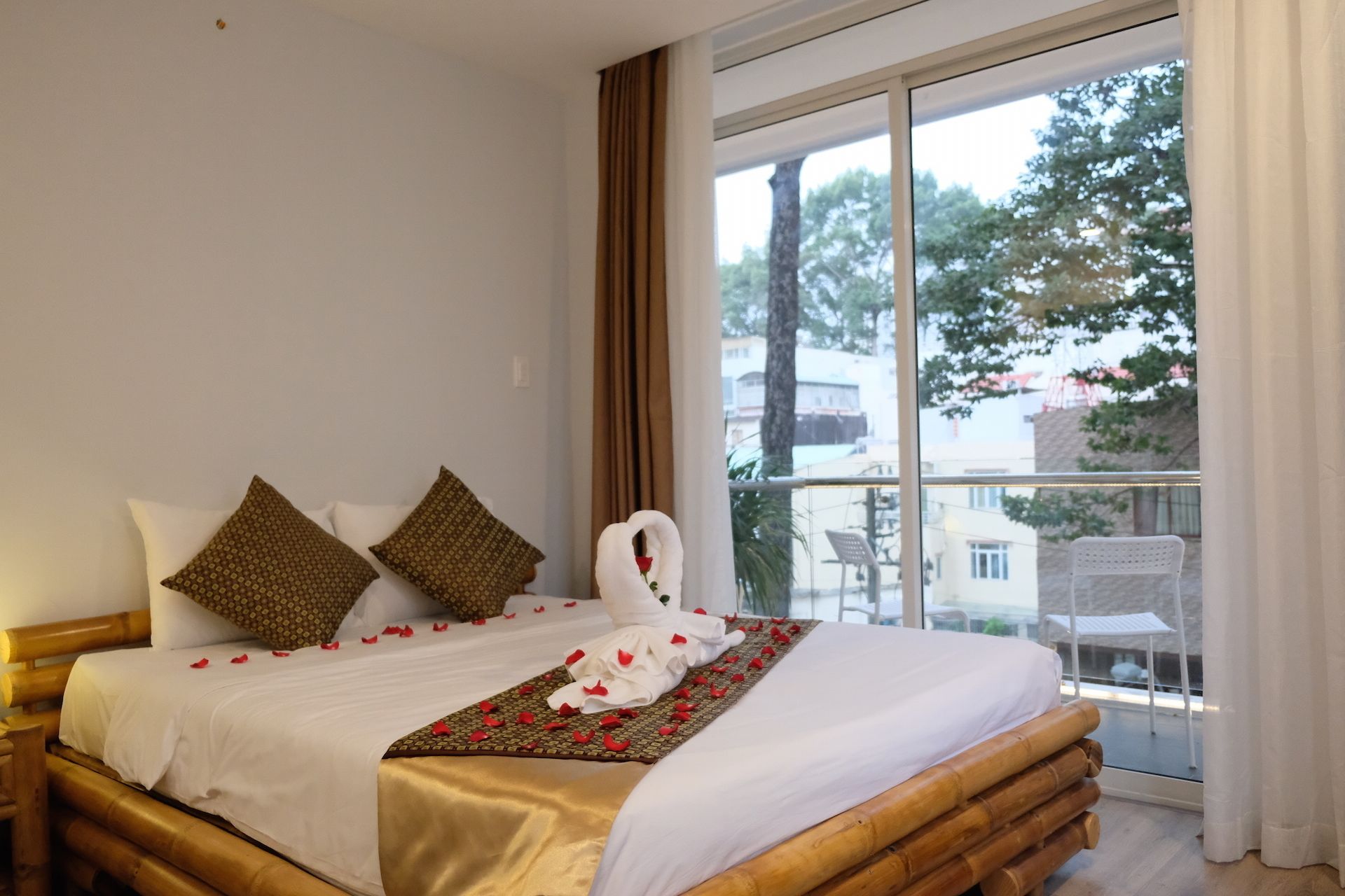A neatly made bed with a white and gold bedspread, two patterned pillows, and a swan-shaped pillow.