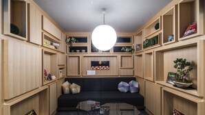 Una sala de estar moderna con un sofá negro, estanterías de madera y una mesa de centro de vidrio.