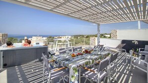 Tagterrasse med spiseplads, jacuzzi og havudsigt.