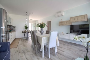 A modern kitchen with white cabinets, a built-in oven, and a dining area with a table set for four.