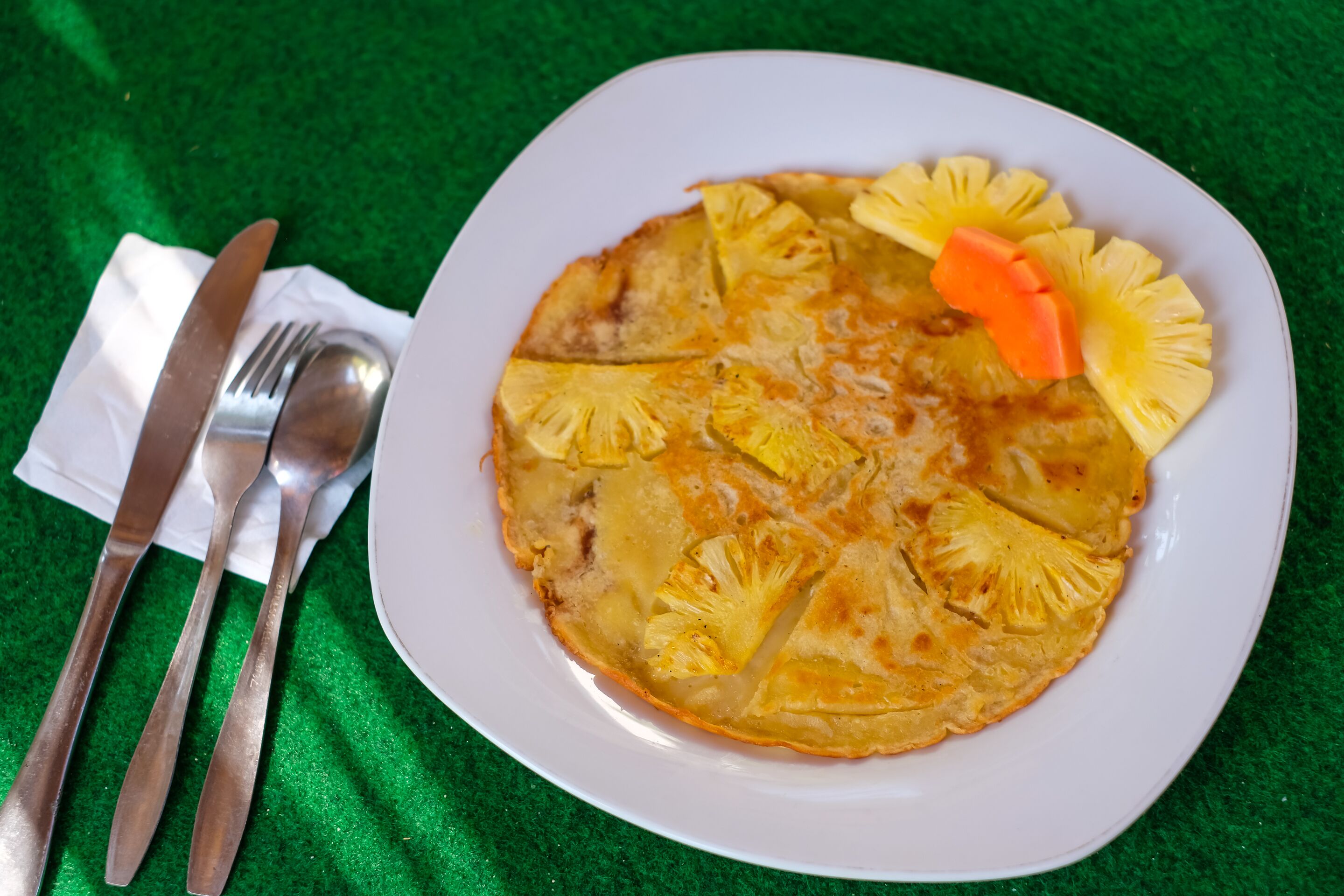 A plate with a pineapple slice and a carrot on a white plate.