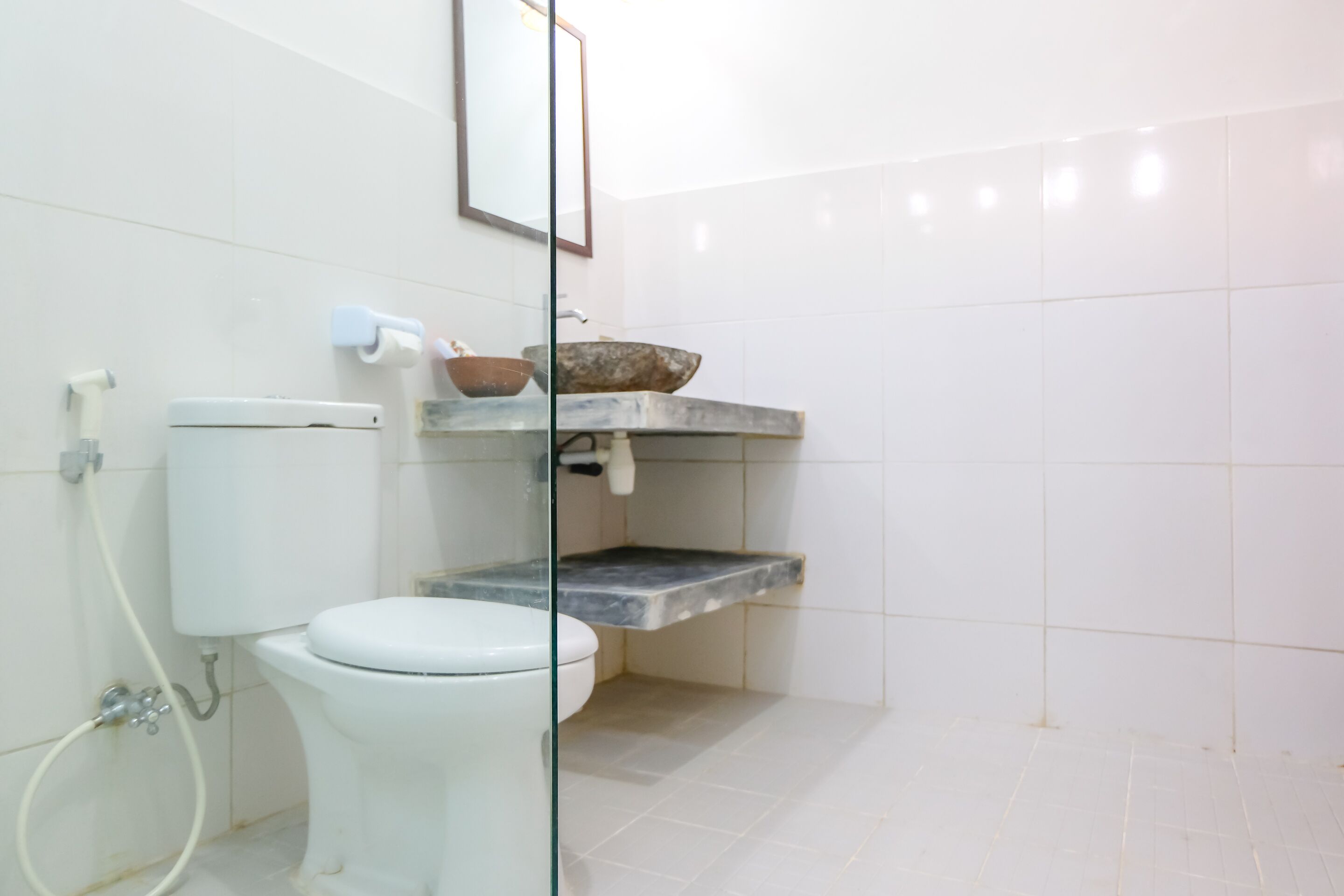 A bathroom with a toilet, a sink with a stone basin, and a mirror on the wall.