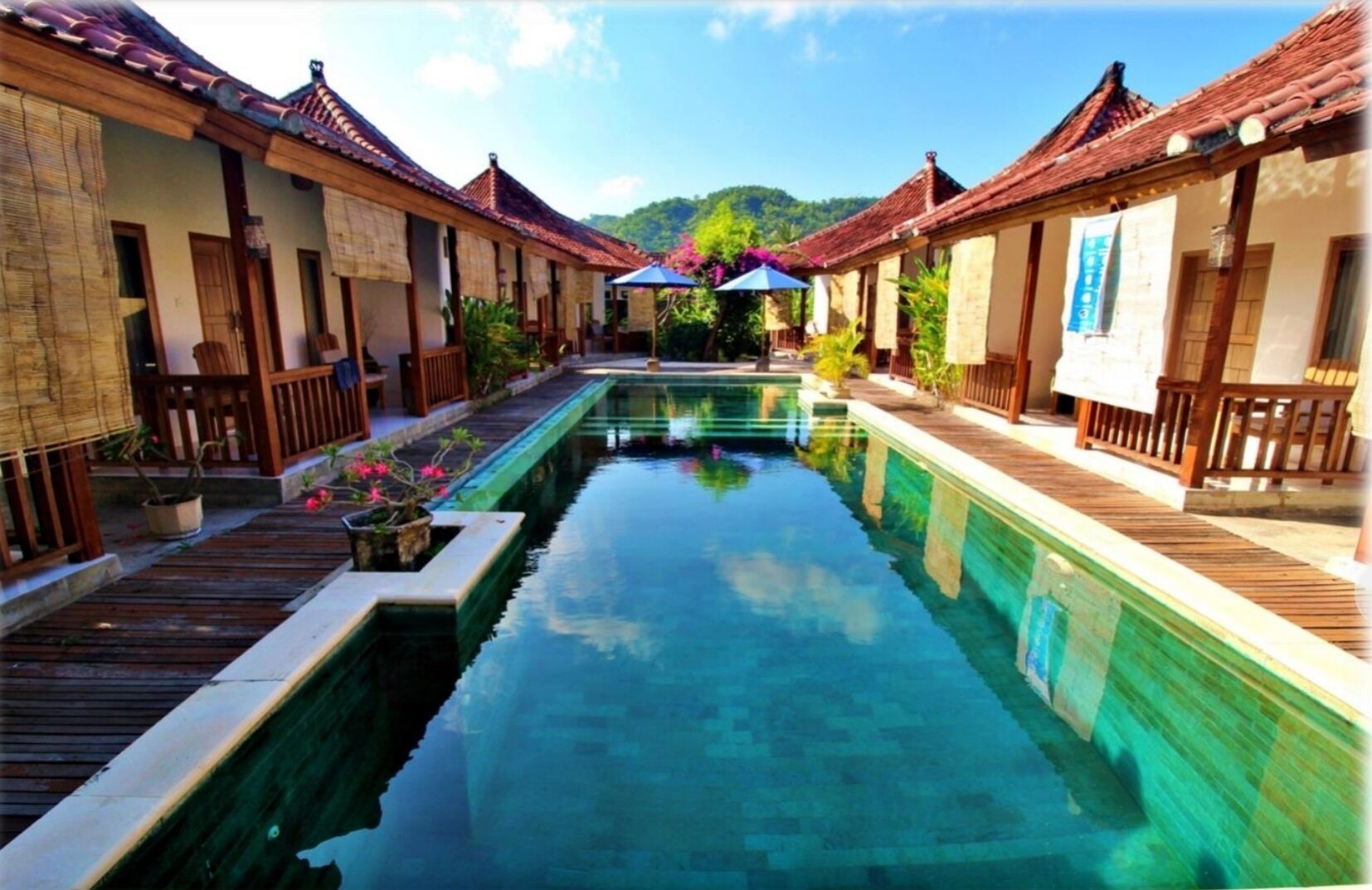 A pool with wooden walkways and traditional buildings with tiled roofs.