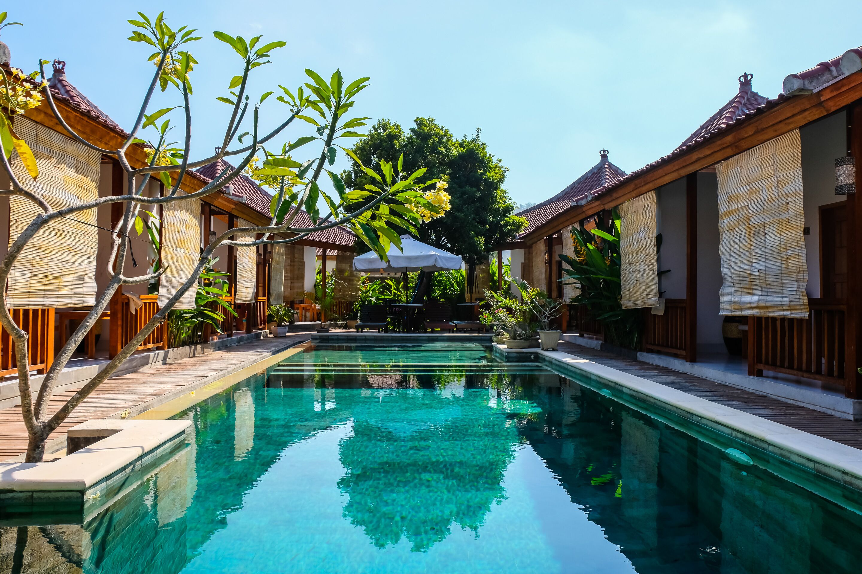 A pool area with tiled flooring, wooden railings, and a clear blue pool.