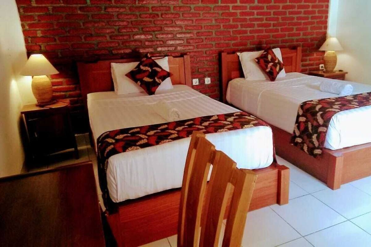 Een hotelkamer met twee bedden, een bakstenen muur, houten meubels en lampen.