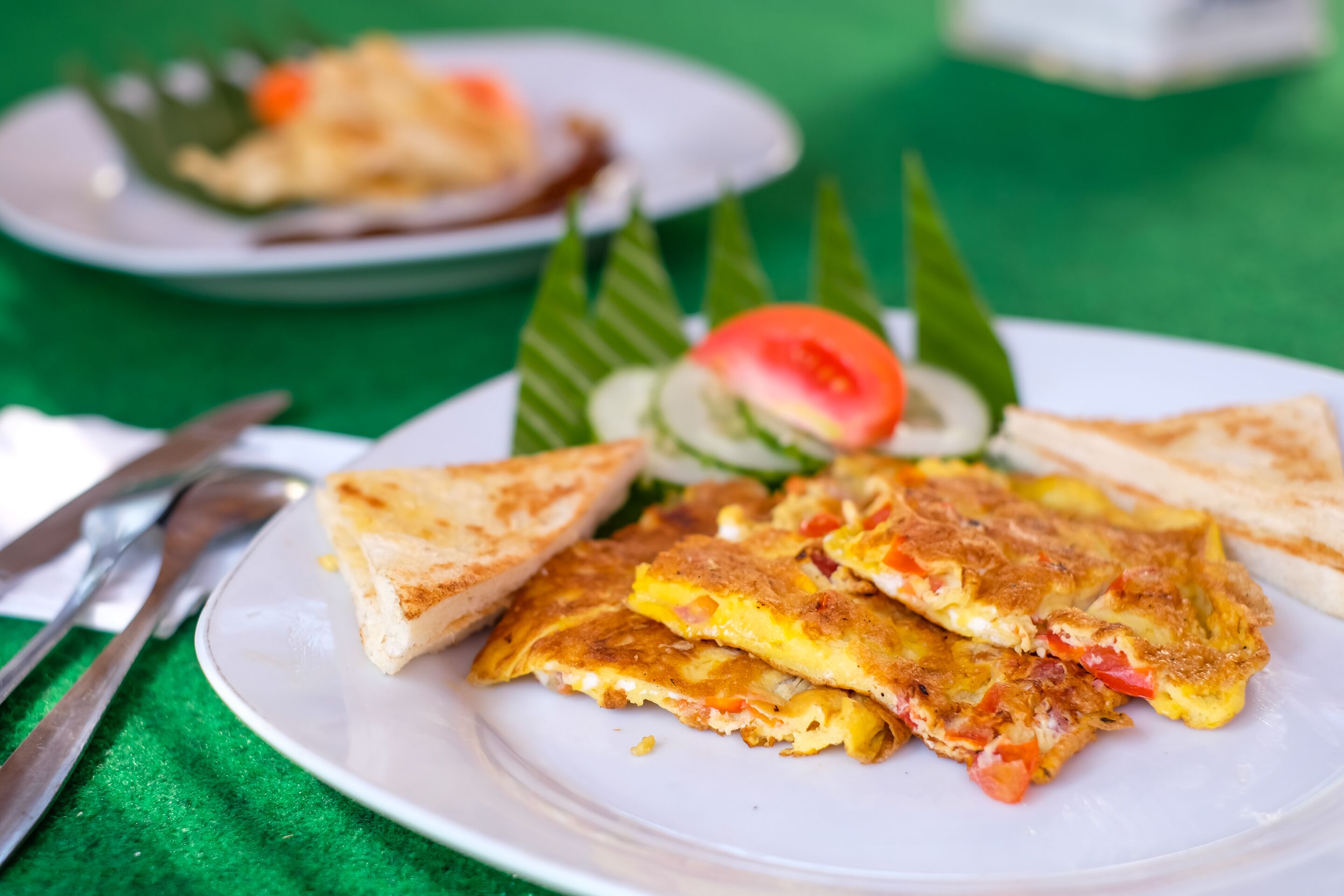 A plate of food with a slice of tomato, a piece of cucumber, and a piece of toast.