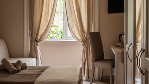 Ein Hotelzimmer mit Bett, Schreibtisch, Stuhl und einem an der Wand befestigten Fernseher.