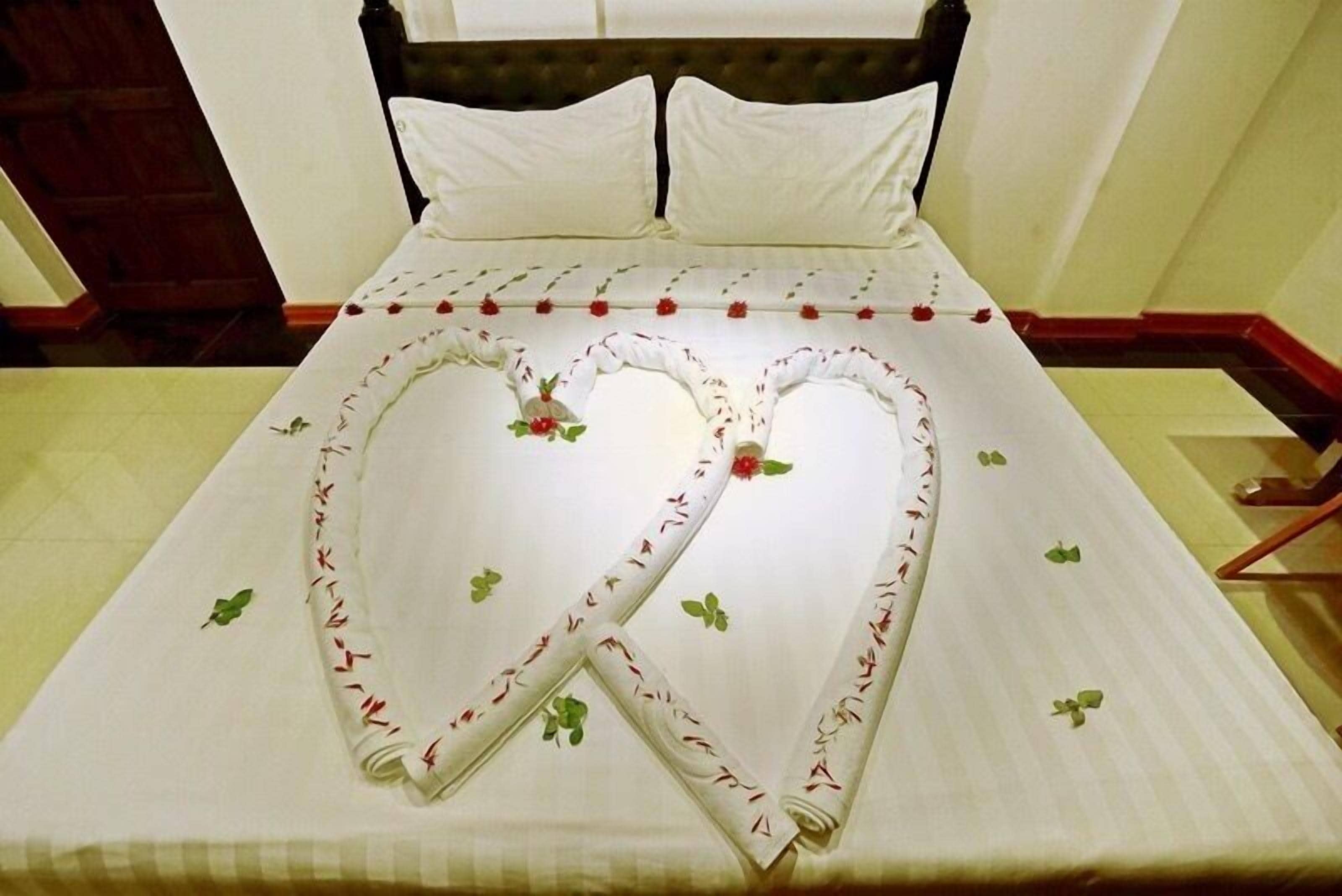 Un lit avec un ensemble de linge de lit orné d’un motif en forme de cœur et d’un motif floral.