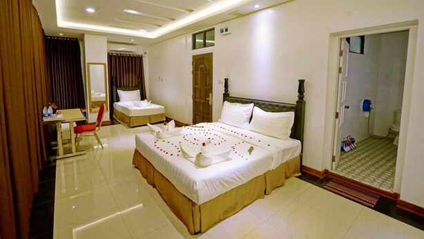 A hotel room with a large bed, a desk, and a chair. - Mandalay Hill View Inn (Mandalay)