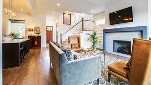 A modern living room with a sofa, a fireplace, and a TV mounted on the wall. - Close to Broadway · Rooftop Skyline · Walkable (Nashville)