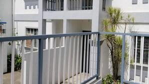 Un edificio a più piani con pareti bianche, balconi con ringhiere nere e un ingresso chiuso da cancello.