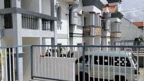 Un edificio moderno con facciata bianca, diversi balconi e un ingresso chiuso da cancello.