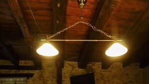 A dining area with a stone wall, wooden ceiling beams, and a white tablecloth-covered table with four wooden chairs. - Country house in the heart of Black Périgord (Dordogne)