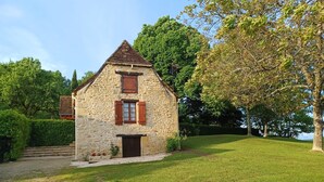 A stone house with a pitched roof, wooden shutters, and a small front porch. - Country house in the heart of Black Périgord (Dordogne)