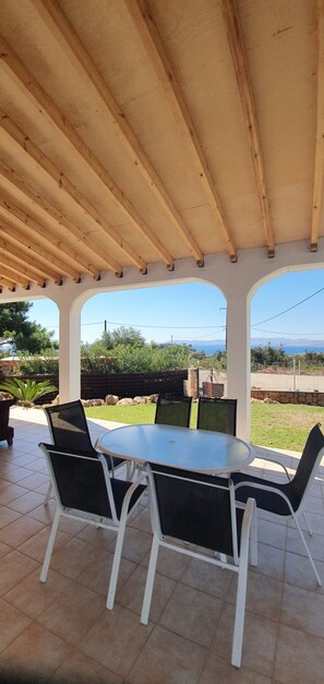 An outdoor patio with a wooden pergola, a round table, and four chairs.