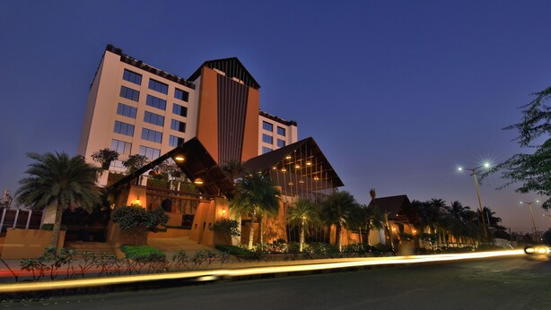 A modern hotel with a prominent tower, multiple balconies, and well-lit outdoor areas.