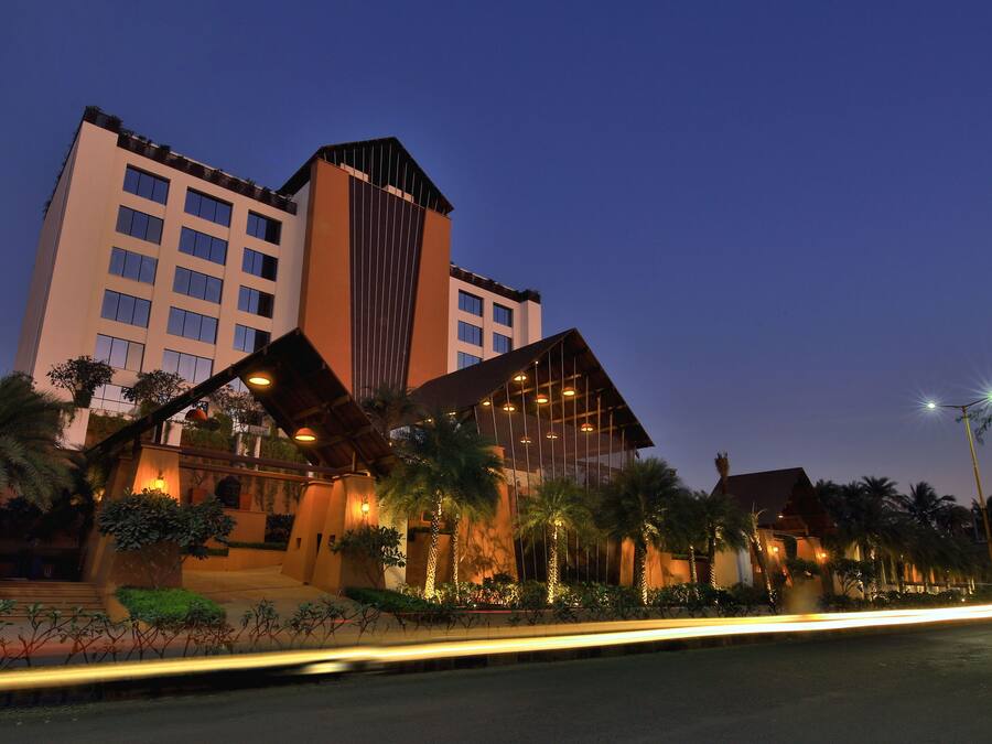 A modern hotel with a prominent tower, multiple balconies, and well-lit outdoor areas.