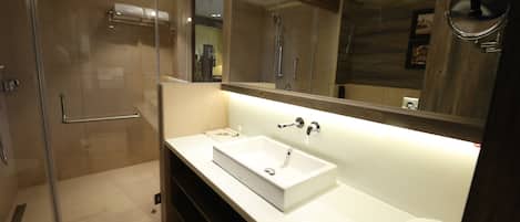 A modern bathroom with a glass shower enclosure, a white sink, and a large mirror.