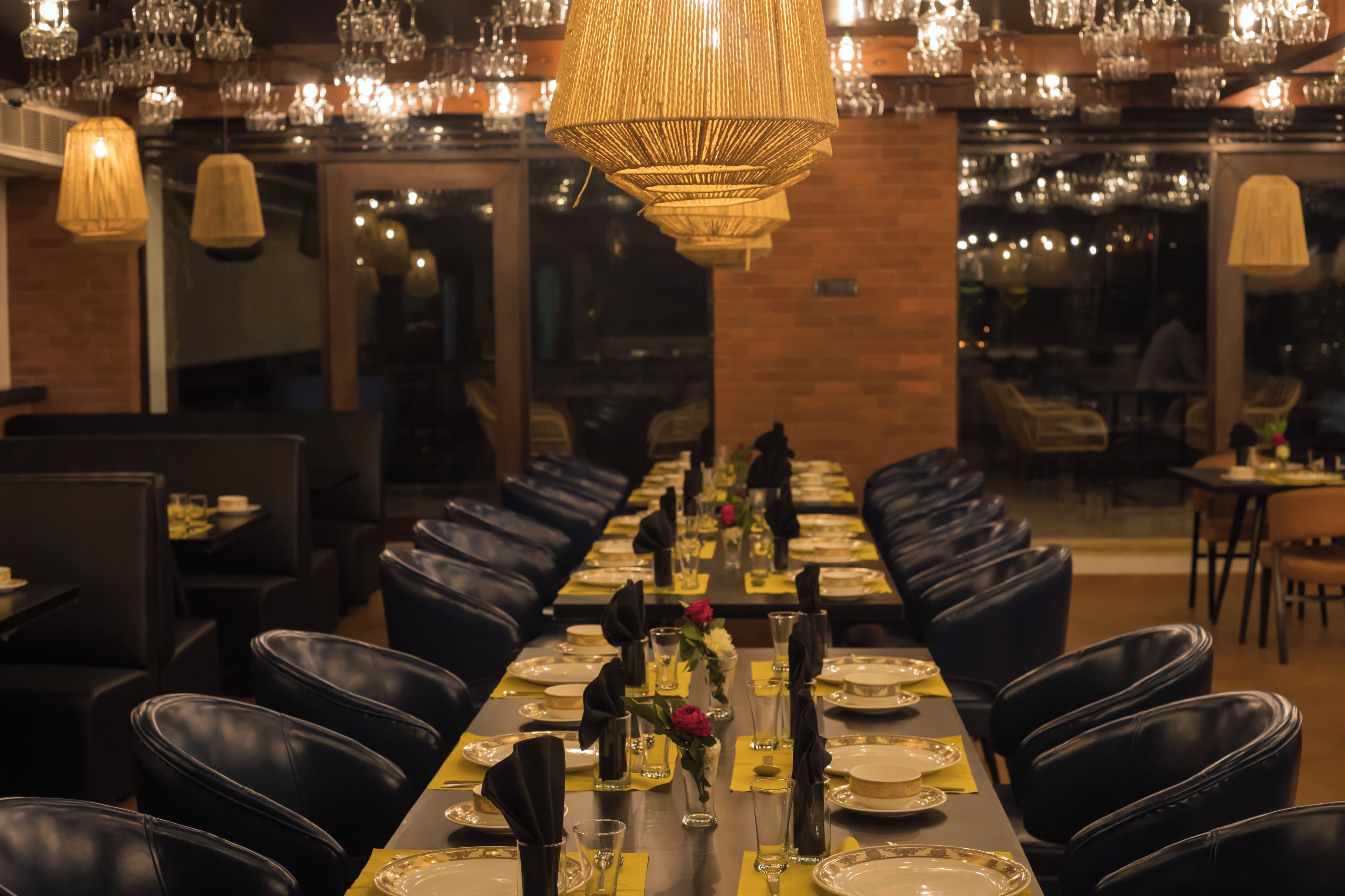 Une longue table à manger, entourée de nombreuses chaises, agrémentée de verres et d’un centre de table.
